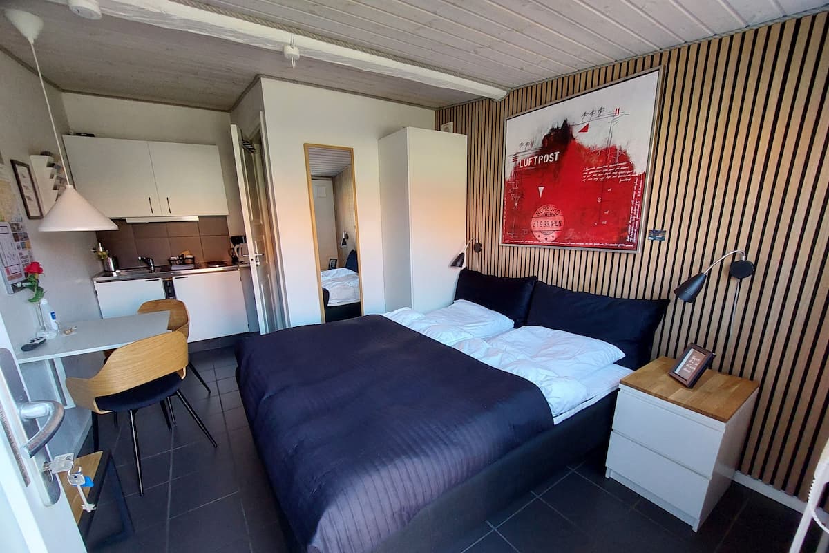 A compact hotel room with a bed, a desk, and a kitchenette.