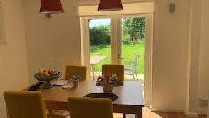 Uma sala de jantar com uma mesa, cadeiras e uma tigela de frutas.