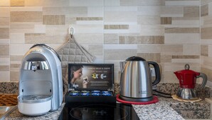 A coffee machine, a kettle, and a coffee maker on a kitchen counter with a tiled backsplash.