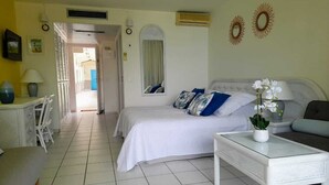 Habitación de hotel con cama, sofá, una mesita y una silla. Se ve una puerta que da a otra habitación.