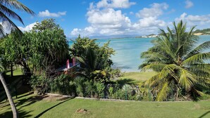 Un paisaje tropical con vista despejada al mar, exuberante vegetación y un área cercada.