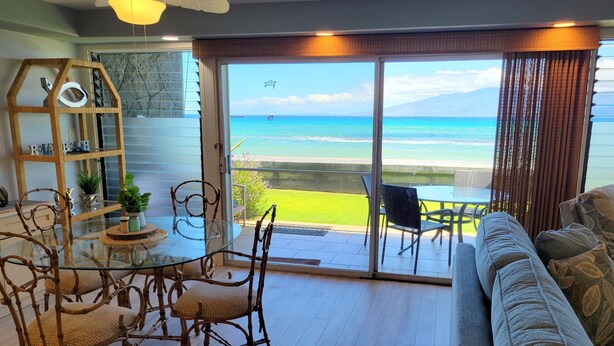 Een woonkamer met een glazen deur die leidt naar een balkon met uitzicht op de oceaan.
