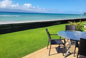 A patio with a table and chairs overlooking a grassy area and the ocean. - Exquisite Direct Sunset & Oceanview 4 Miles! Pool (Lahaina)