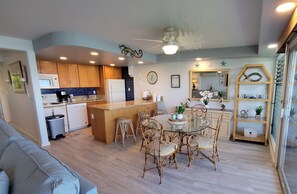 Une cuisine moderne avec des meubles en bois, un îlot central et un coin repas doté de chaises en osier.