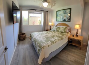 A bedroom with a bed, two bedside lamps, a wall-mounted TV, and a window with curtains. - Exquisite Direct Sunset & Oceanview 4 Miles! Pool (Lahaina)