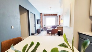 A modern living room with a sofa, a dining table, and a kitchen area with cabinets and a countertop. - Stay Lincoln Park 1 | Craft District Condo (Duluth)