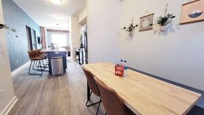 A modern kitchen with a wooden table and chairs, a refrigerator, and a sink. - Stay Lincoln Park 1 | Craft District Condo (Duluth)