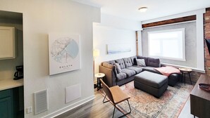 A modern living room with a sectional sofa, a small table, and a coffee machine. - Craft District Pet-Friendly Condo by Heirloom (Duluth)