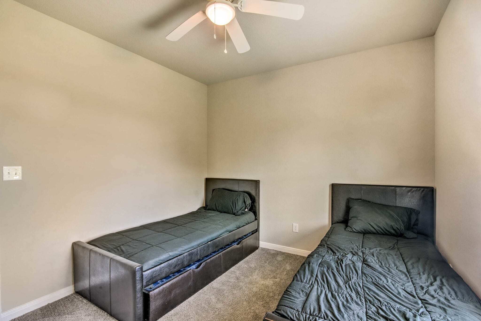 Eine kleine Wohnung mit einem Schlafzimmer, zwei Betten, einem Deckenventilator und Teppichböden.