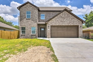 A two-story house with a brick exterior, a front garage, and a well-maintained lawn. - Brand New! Fully Furnished Texas City Home (Houston)