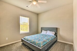 Ein Schlafzimmer mit einem Bett, einem Deckenventilator, einem Fenster und einem Teppichboden.
