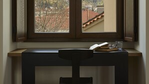 A room with a desk and chair, a window with a view of a mountain and buildings. - The Storyteller House (Kalabaka)