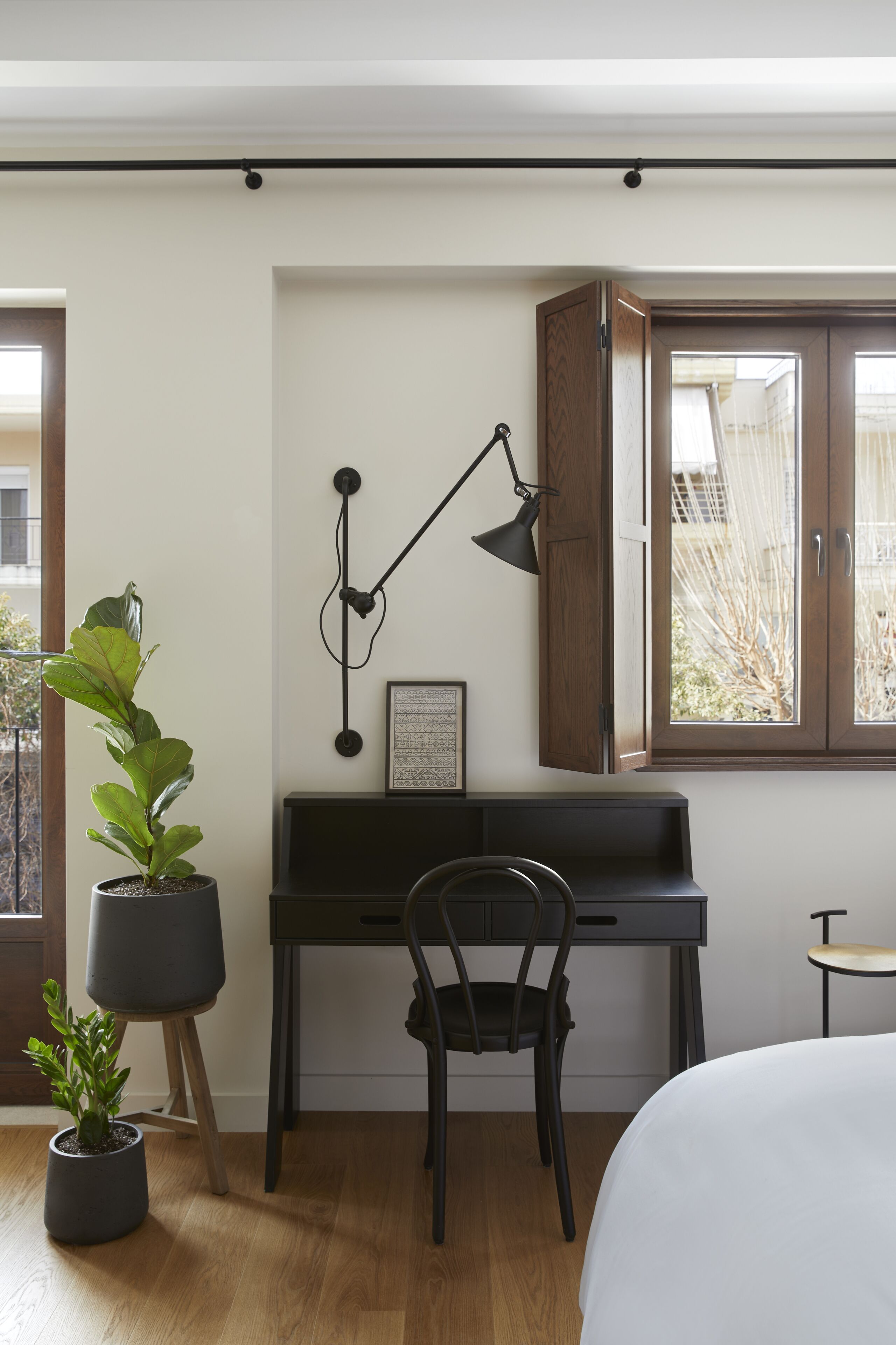 Una habitación con un piano, un escritorio, una silla, una cama y dos plantas en macetas.