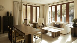 A spacious living area with a wooden dining table, comfortable seating, and large windows offering natural light and views. - The Storyteller House (Kalabaka)