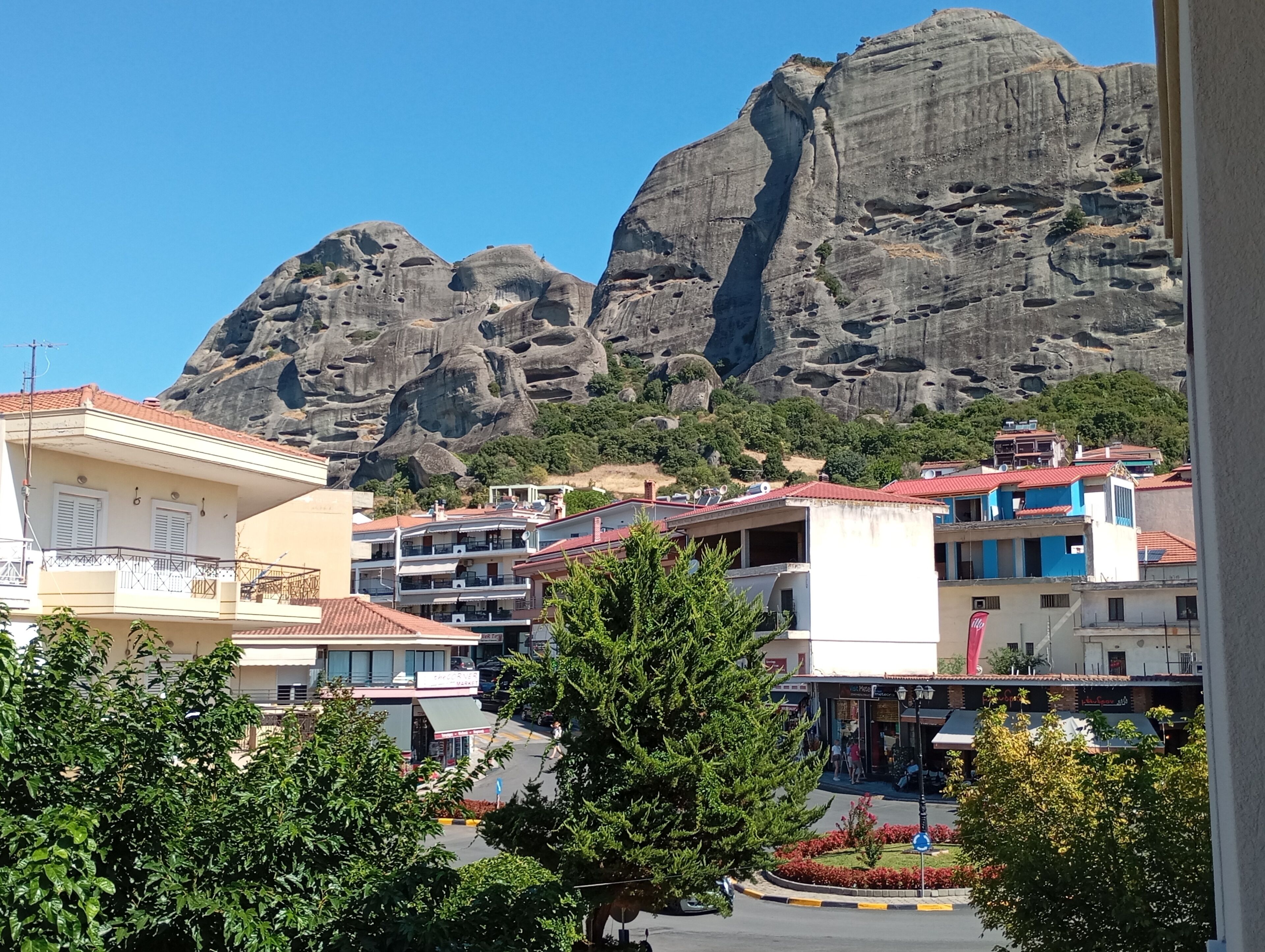 A coastal town with buildings in the foreground and a large rock formation in the background.