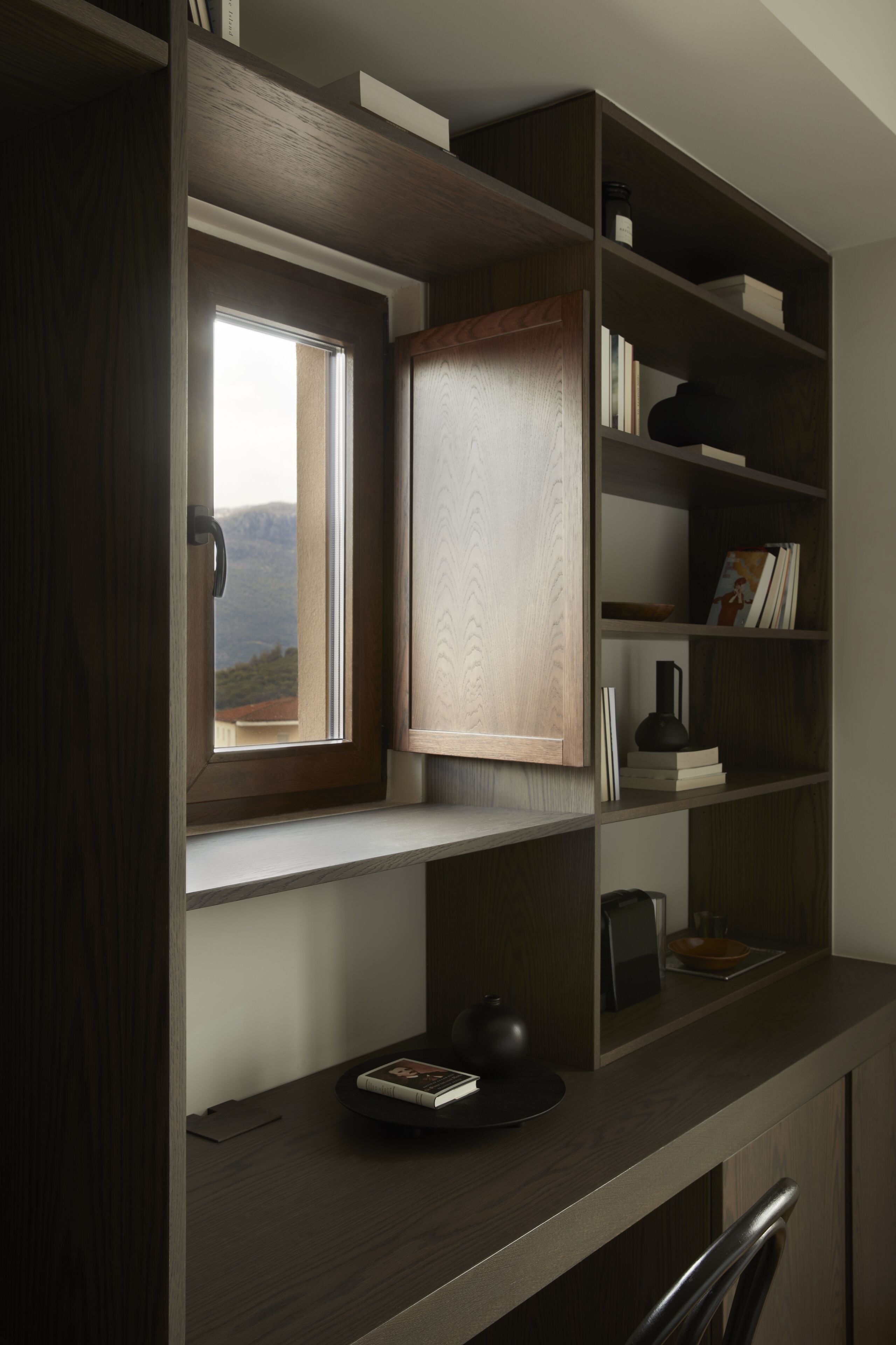 A room with a built-in window, wooden shelves, and a desk with a kettle and books.