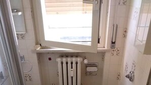 Ein Badezimmer mit zwei Toiletten, einem Waschbecken, einer Dusche und einem Fenster.