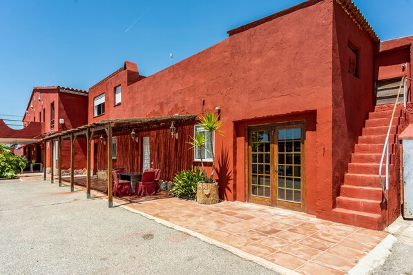 A red building with a covered patio, a staircase, and a door. - Finca Escalicha (Cambrils)