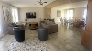 Un salón amplio con un sofá, dos sillones, una mesa de centro y un comedor con mesa y sillas.
