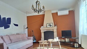 A living room with a sofa, a fireplace, a TV, and a guitar.
