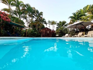 Una piscina cristallina circondata da palme e un edificio in legno.
