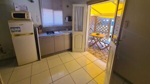 Una cocina compacta con refrigerador, microondas, pileta y un pequeño comedor con mesa y sillas.