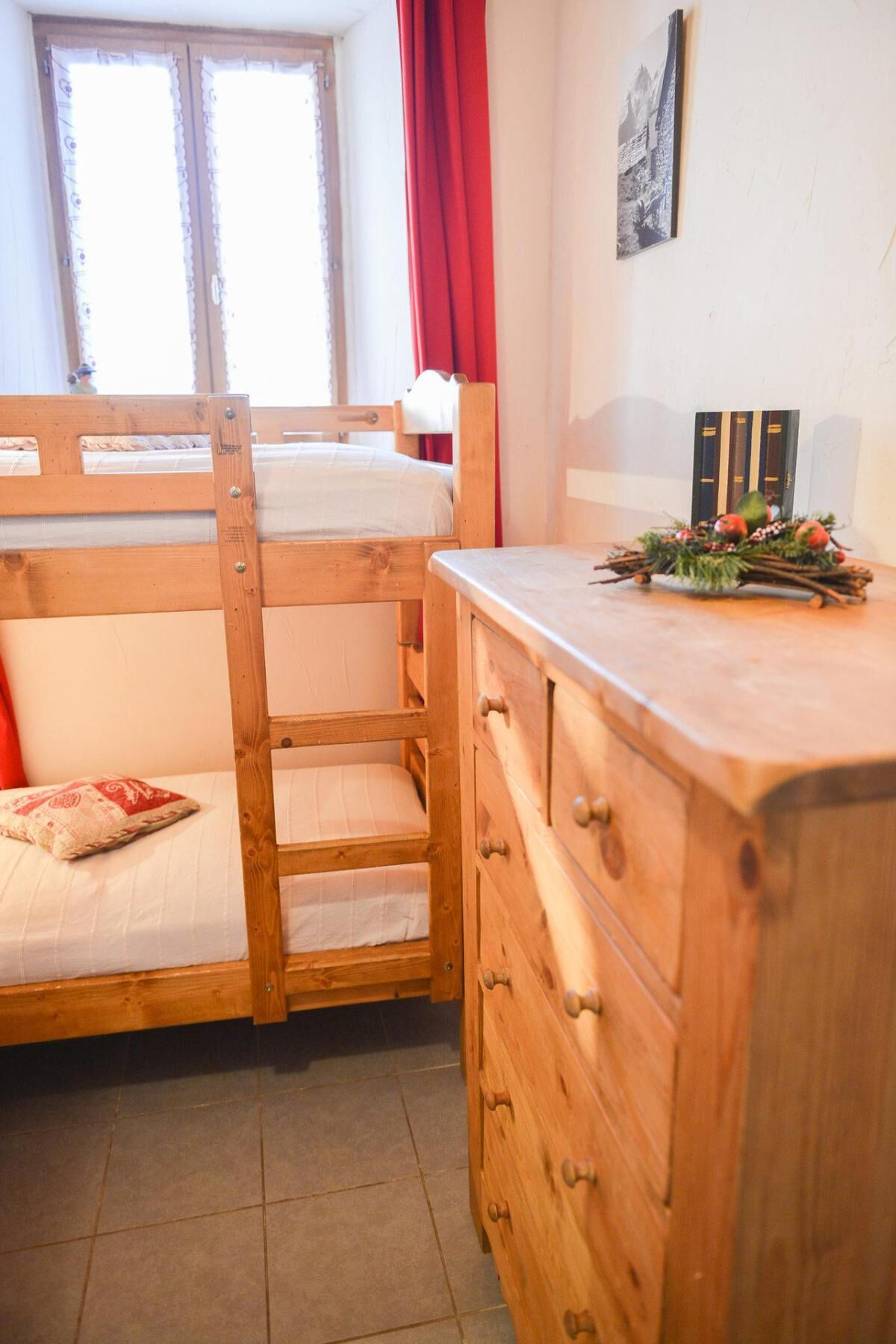 A bunk bed with a wooden headboard, a small bedside table, and a dresser with drawers.