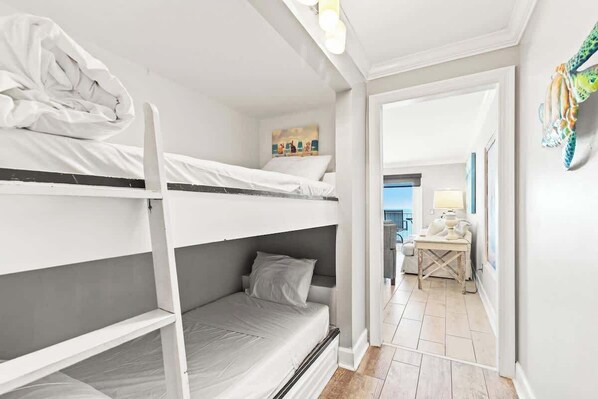 Une chambre avec des lits superposés, un bureau avec une lampe et un tableau accroché au mur.