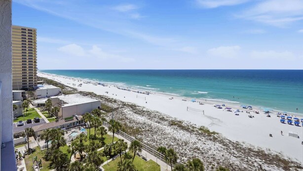 A beach view with a hotel, sandy beach, and ocean.