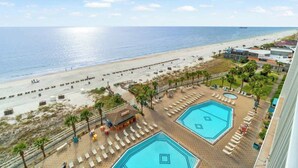 A beachside hotel with two swimming pools, a beach, and a view of the ocean.