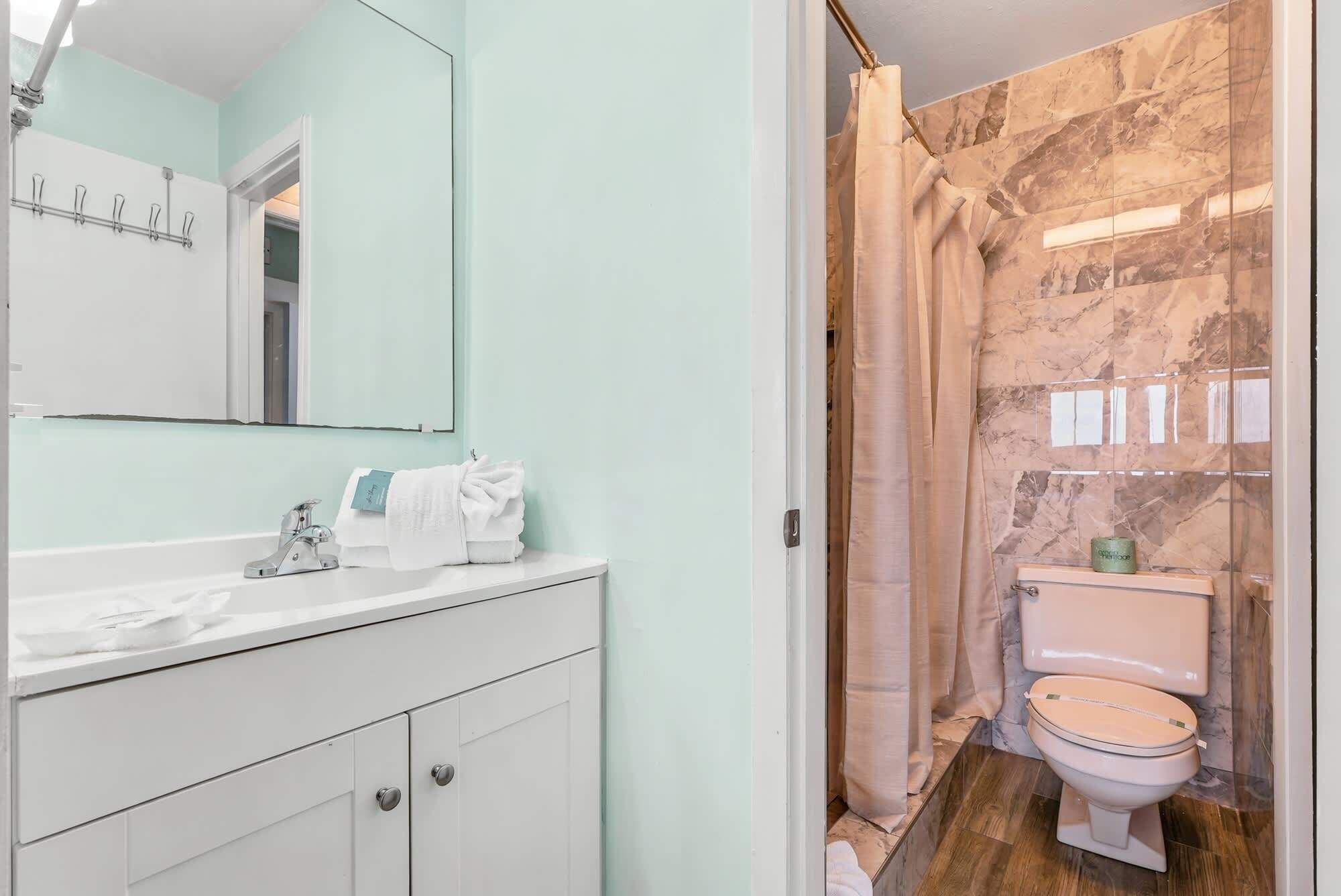 A bathroom with a white vanity, a mirror, and a shower curtain.