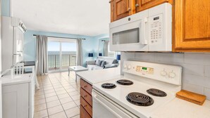 A compact kitchen with a microwave, stove, and wooden cabinets.
