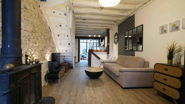 A spacious living area with a fireplace, a sofa, a coffee table, and a staircase leading to an upper level.