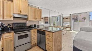 A compact kitchen with wooden cabinets, a stove, and a dishwasher. - Top Of The Gulf 111 - Ground Level Studio (Panama City Beach)