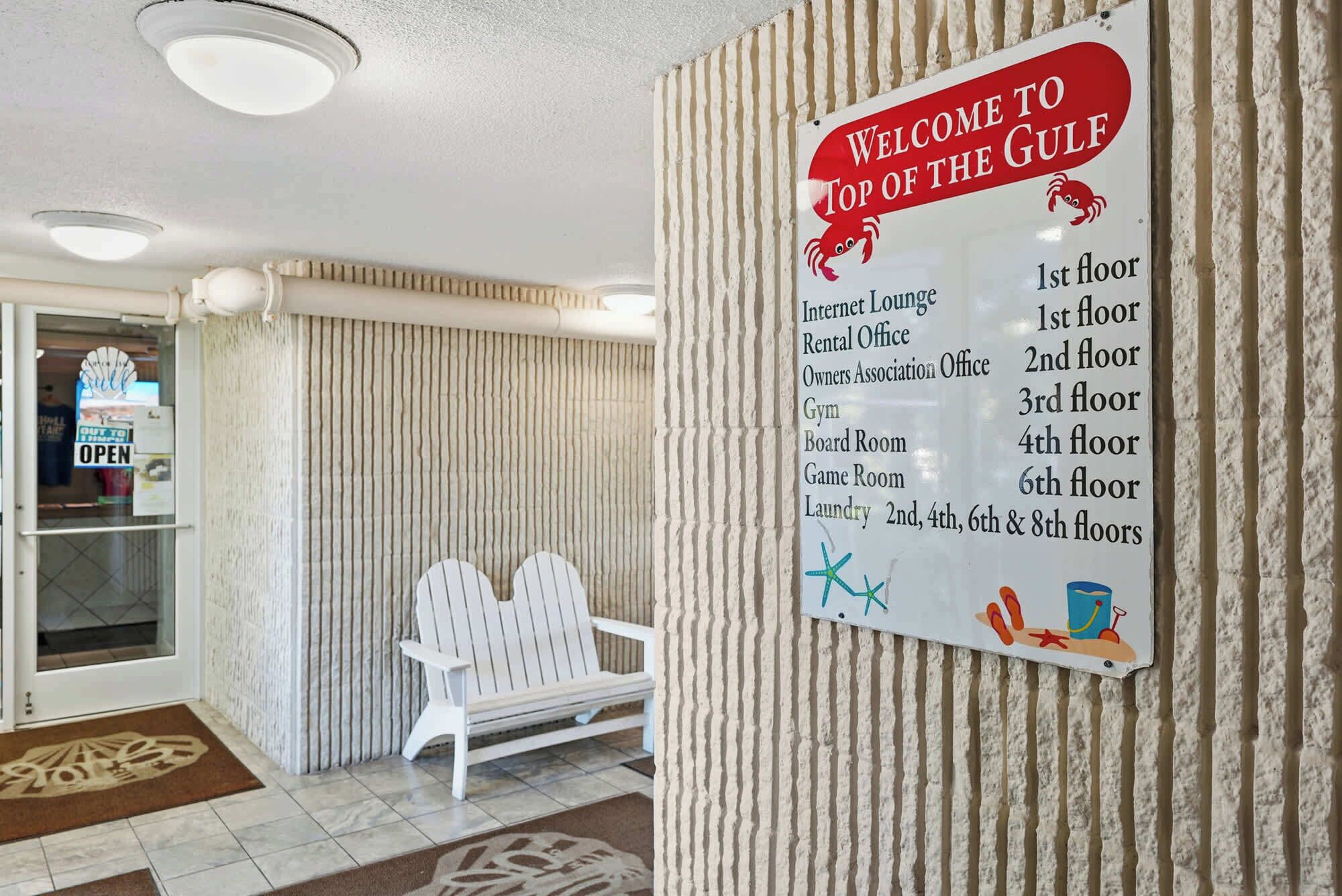 A welcome sign at the entrance of a building with a beach theme, listing various amenities and their locations on different floors. - Top Of The Gulf 111 - Ground Level Studio (Panama City Beach)