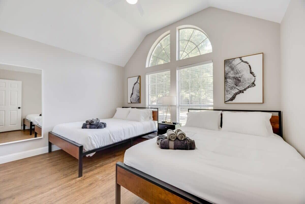 Une chambre d’hôtel avec deux lits, une grande fenêtre et des œuvres d’art accrochées aux murs.