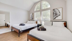 Quarto de hotel com duas camas, uma janela grande e obras de arte nas paredes.