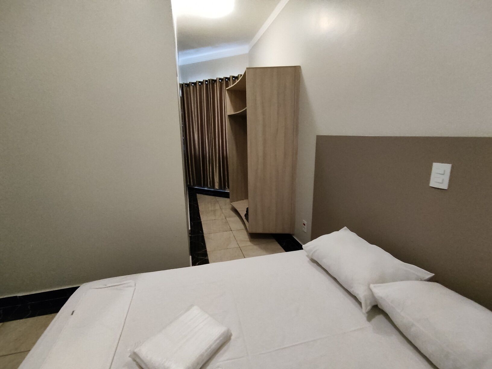 Une chambre d’hôtel avec un lit, une table de chevet et une armoire.