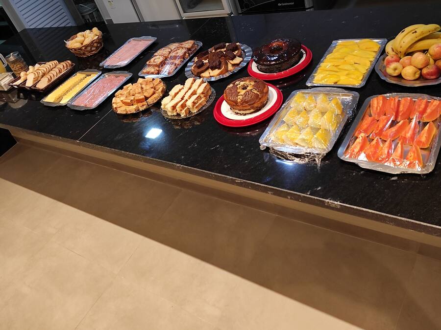 A buffet table with various food items including bread, cheese, meats, desserts, and fruits.