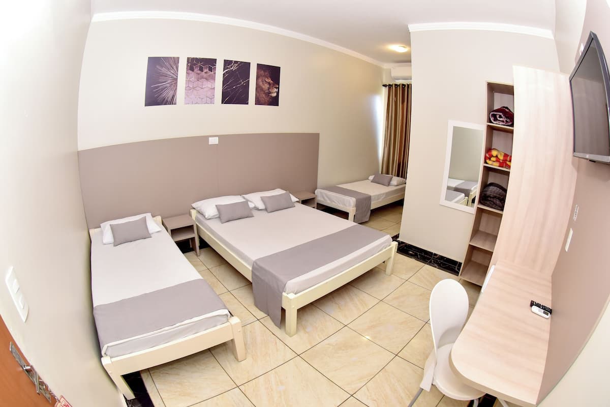 Habitación de hotel con dos camas, un escritorio, una silla, un televisor y un armario.