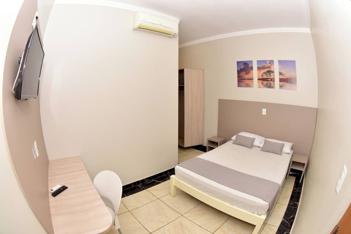 Un dormitorio con cama, escritorio, silla, armario y televisor.