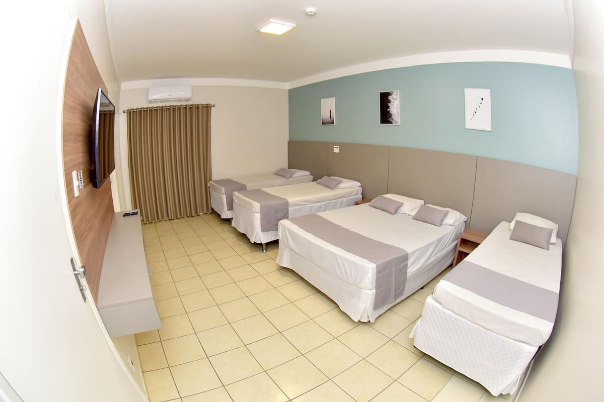 Una habitación de hotel con dos camas, televisión, aire acondicionado y una cortina.