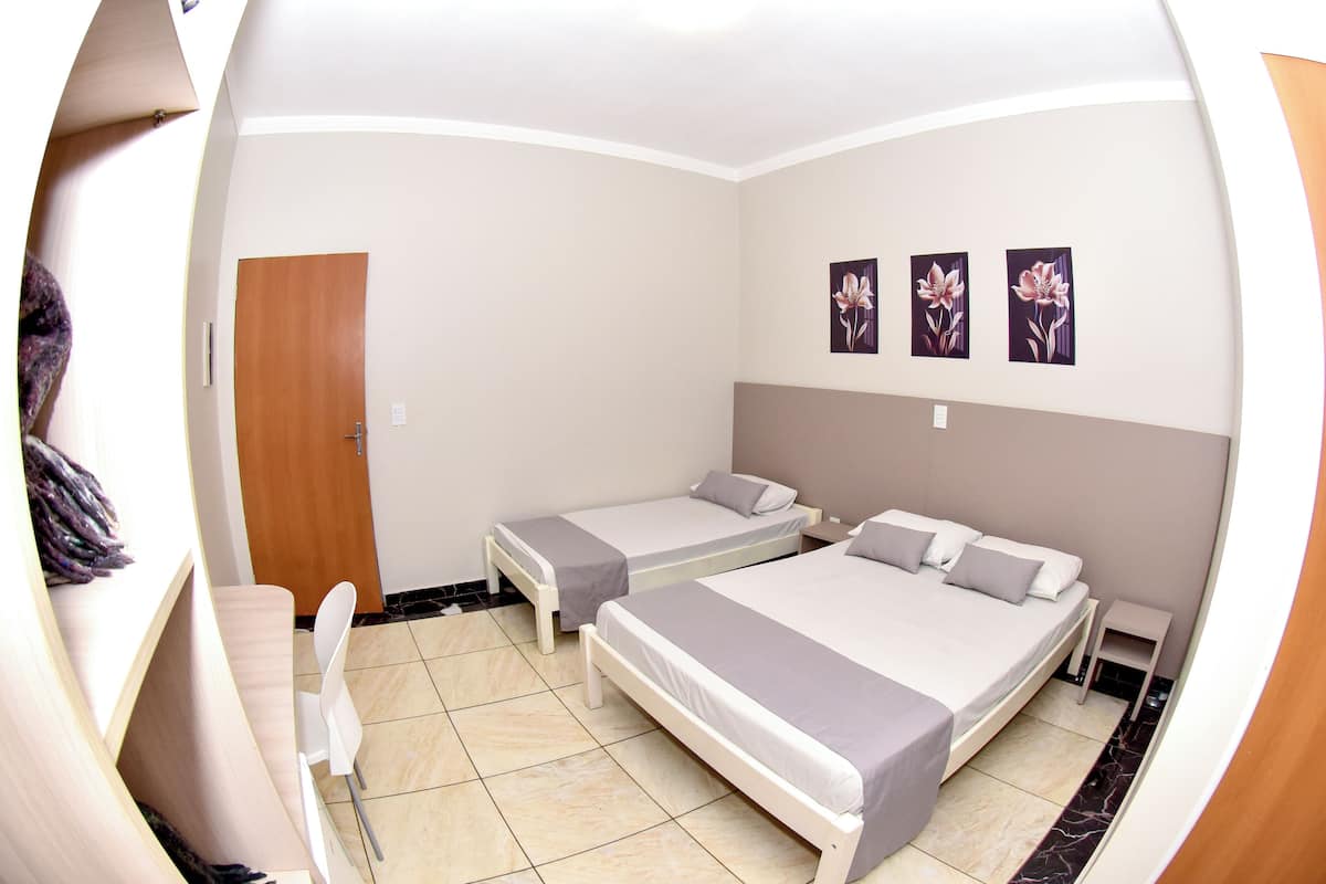 Una habitación con dos camas individuales, una puerta de madera y una pequeña mesa con una silla.