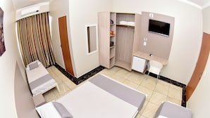 A hotel room with two beds, a desk, a TV, a wardrobe, and a bathroom.