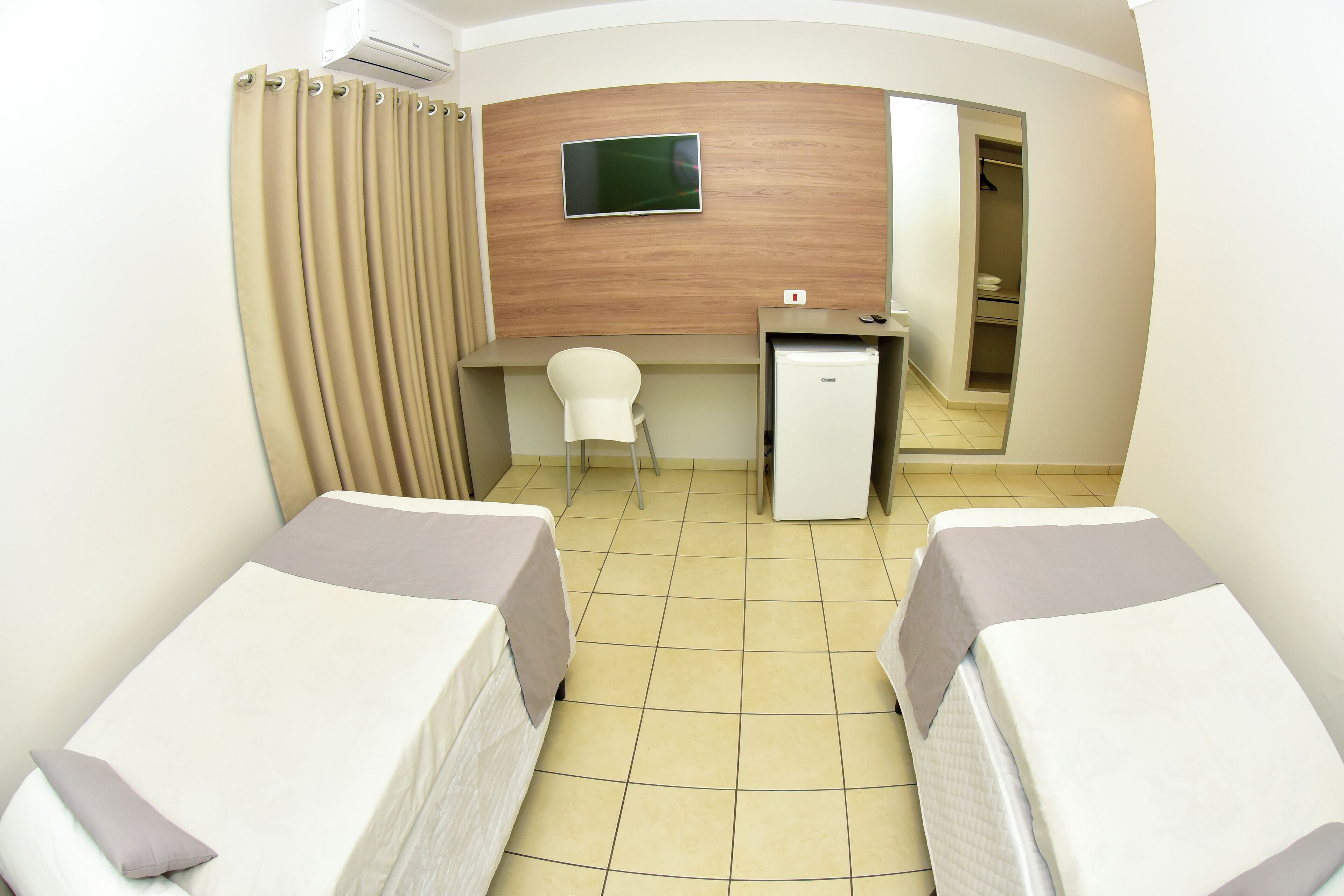 Una habitación de hotel con dos camas, un escritorio, una silla y un televisor.
