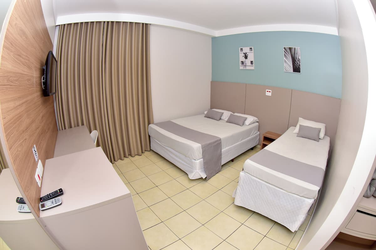 Una habitación de hotel con dos camas, un escritorio, un televisor y una cortina.