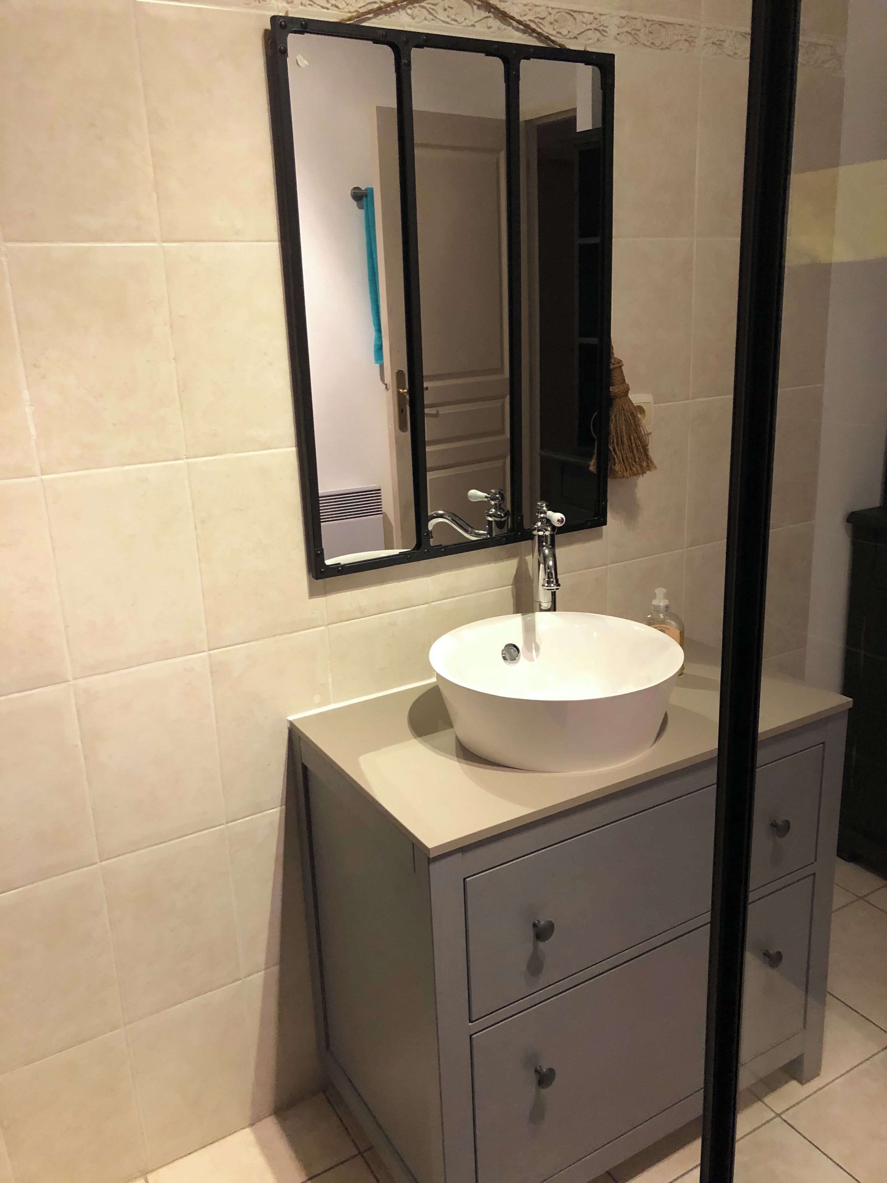 Een badkamer met een witte wastafel, een spiegel en een handdoekhouder.