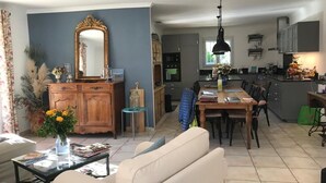 Ein geräumiges Wohnzimmer mit einer Couch, einem Couchtisch und einem Essbereich mit Tisch und Stühlen. Es gibt eine Küchenzeile mit Schränken und einer Arbeitsplatte.