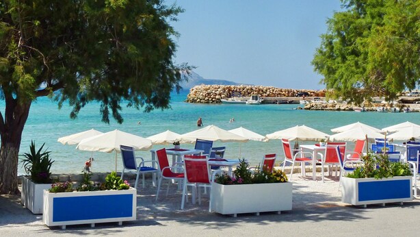 A beachside café with outdoor seating, including tables and chairs, and umbrellas. - Villa Metapothia in Gavalohori (Apokoronas)