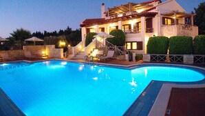 A swimming pool with a stone deck, lounge chairs, and a staircase leading to a second floor with a balcony. - Villa Metapothia in Gavalohori (Apokoronas)